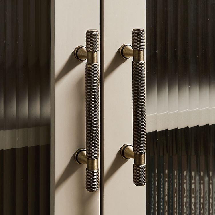 A solid brass Hometouch drawer pull features an antique brass finish and knurled cylindrical form designed for contemporary furniture hardware applications.
