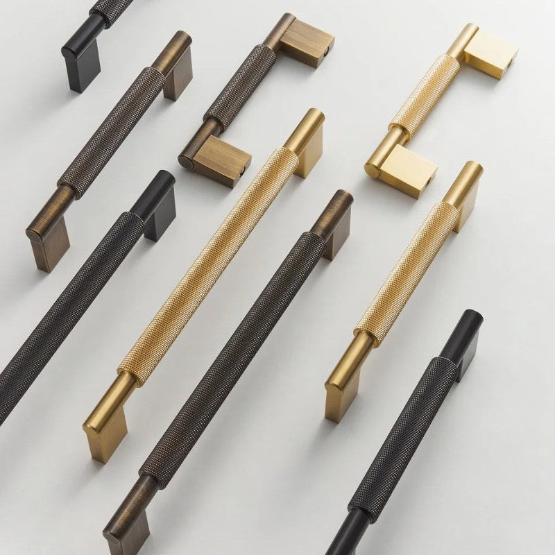 A Hometouch handle in brass with a cross-knurled pull shape is available in black gold and antique brass finishes for cabinet and furniture hardware applications, sourced from www.hometouchware.com.