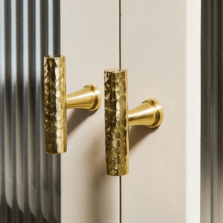 A Hometouch wardrobe handle crafted from hammered golden brass in an oval profile, presented as product photography for furniture hardware documentation or e-commerce use.