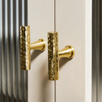 A Hometouch wardrobe handle crafted from hammered golden brass in an oval profile, presented as product photography for furniture hardware documentation or e-commerce use.