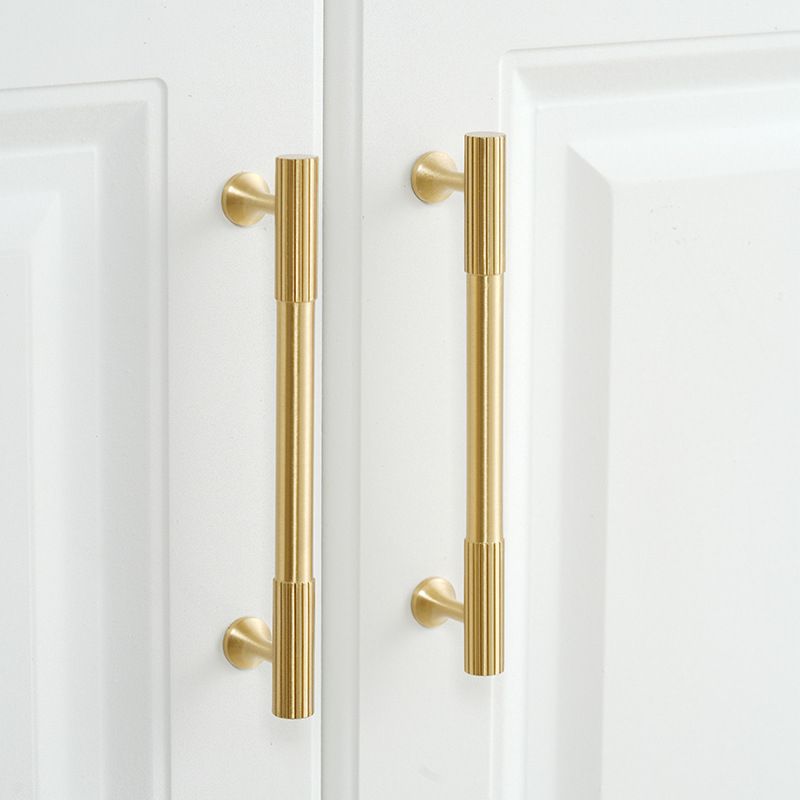 A solid brass cabinet pull with antique finish showcases a vertical knurled texture, designed for modern cabinetry hardware applications and available via www.hometouchware.com.
