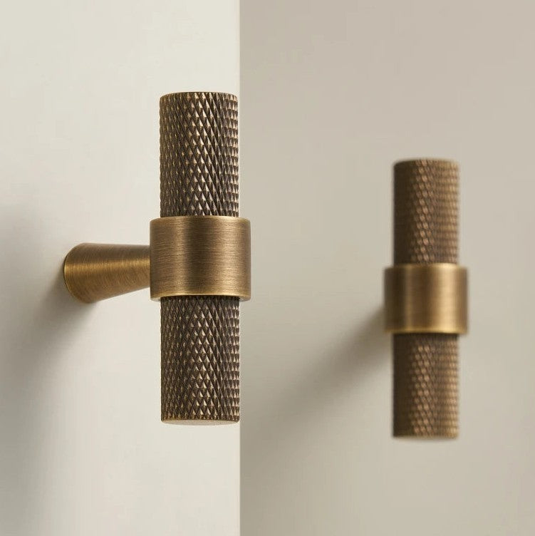 A Hometouch T-bar cabinet pull features textured brass with a bronze finish, designed for modern cabinetry hardware applications in interior design contexts.