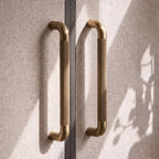 A Hometouch oval cabinet pull in warm gold brass finish appears in clean studio photography ideal for cabinetry and furniture design asset libraries.