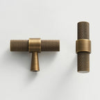 A textured brass dual t-bar door pull handle from Hometouchware photographed against a neutral background, showcasing the product's matte metallic finish and symmetrical linear form for architectural hardware specification or interior design visualization. www.hometouchware.com