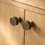 Textured, vintage-inspired cabinet knobs with subtle ridged detailing, ideal for warm wooden cabinetry—by HomeTouch.